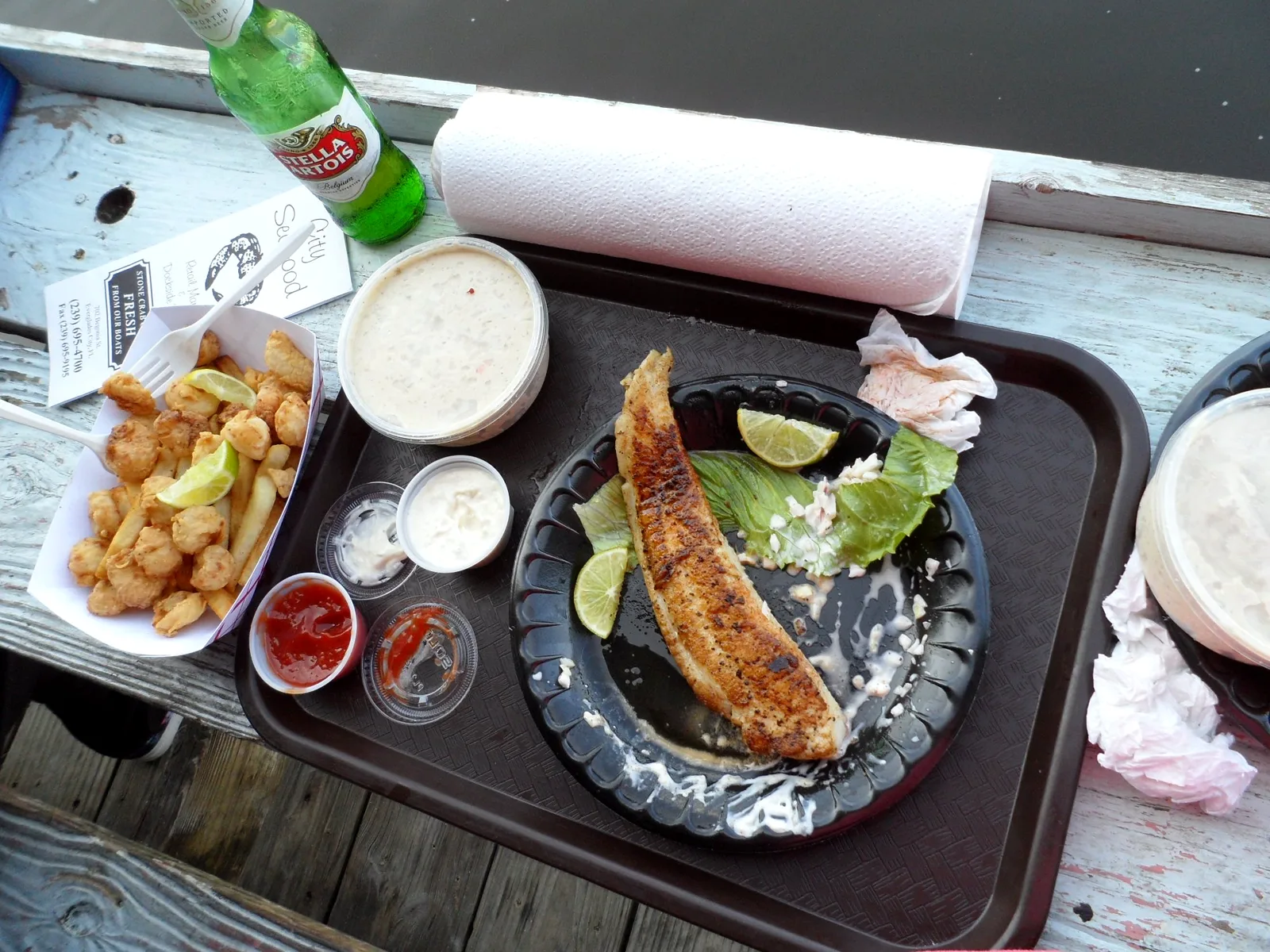 Blackened fish with sides on a tray at a dockside table