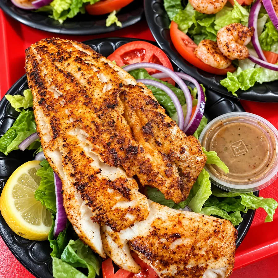 Blackened fish fillets over a salad with grilled shrimp, lemon and dressing